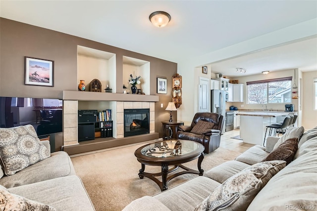 carpeted living room with sink and a tile fireplace