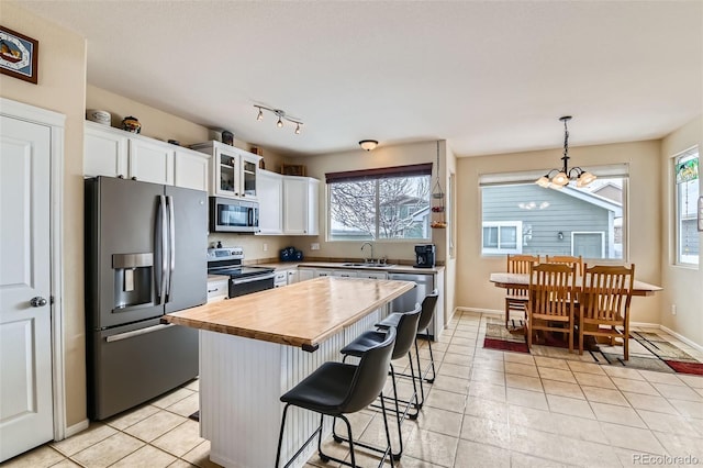 kitchen with stainless steel appliances, white cabinetry, a kitchen island, and hanging light fixtures