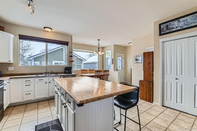 kitchen with white cabinetry, a center island, sink, and pendant lighting