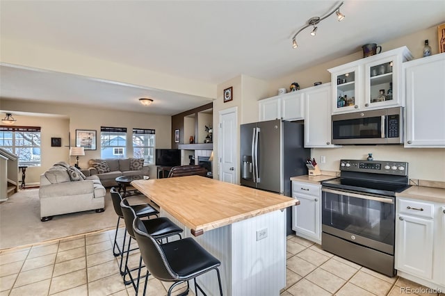 kitchen with white cabinetry, stainless steel appliances, a breakfast bar, and light tile patterned floors