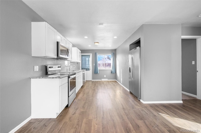 kitchen featuring light stone counters, stainless steel appliances, sink, hardwood / wood-style floors, and white cabinetry