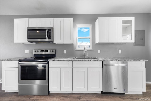 kitchen with appliances with stainless steel finishes, light stone counters, sink, white cabinets, and electric panel