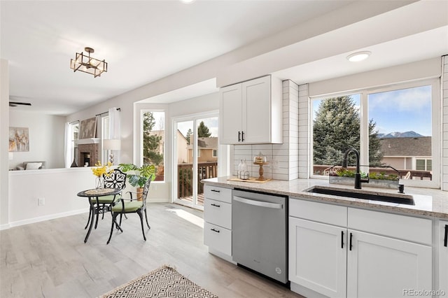 kitchen featuring sink, white cabinets, stainless steel dishwasher, and light hardwood / wood-style flooring