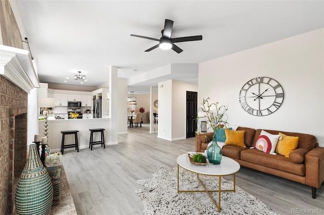 living room with ceiling fan, a fireplace, and light hardwood / wood-style flooring