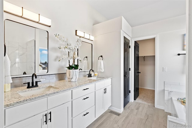 bathroom with hardwood / wood-style floors, decorative backsplash, shower with separate bathtub, and vanity