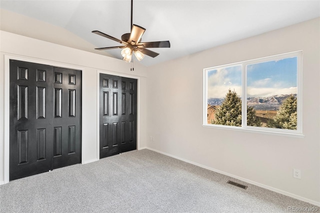 bedroom featuring carpet, ceiling fan, vaulted ceiling, and multiple closets