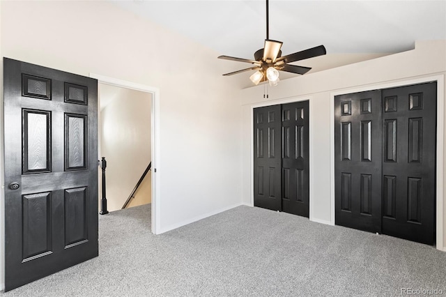 carpeted bedroom with ceiling fan, lofted ceiling, and two closets