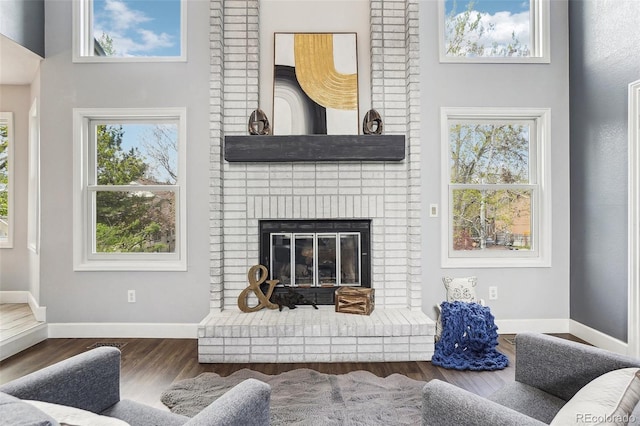 living room with a brick fireplace, baseboards, and wood finished floors