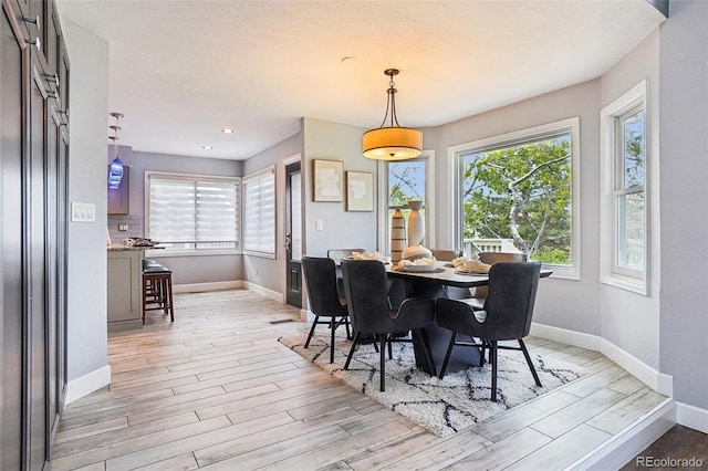 dining space with baseboards and light wood-style floors