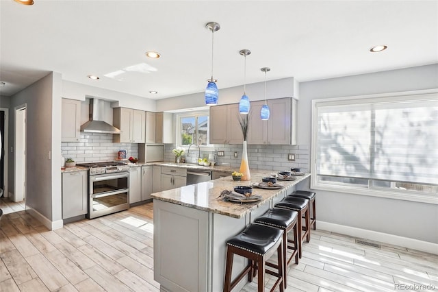 kitchen featuring wall chimney exhaust hood, appliances with stainless steel finishes, and gray cabinetry