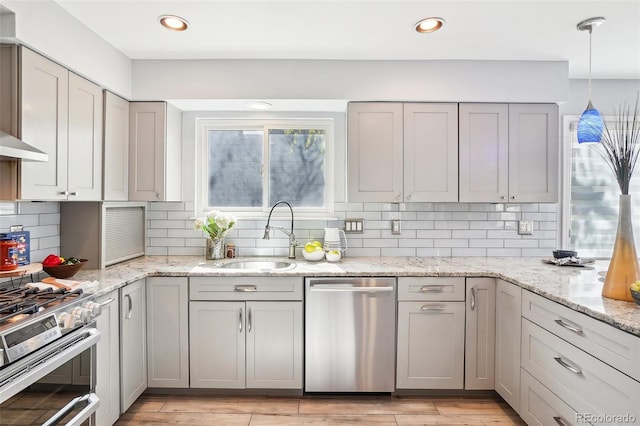 kitchen with appliances with stainless steel finishes, tasteful backsplash, a sink, gray cabinets, and light wood-type flooring