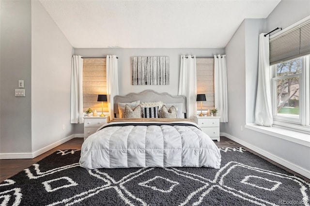 bedroom with baseboards and dark wood-type flooring