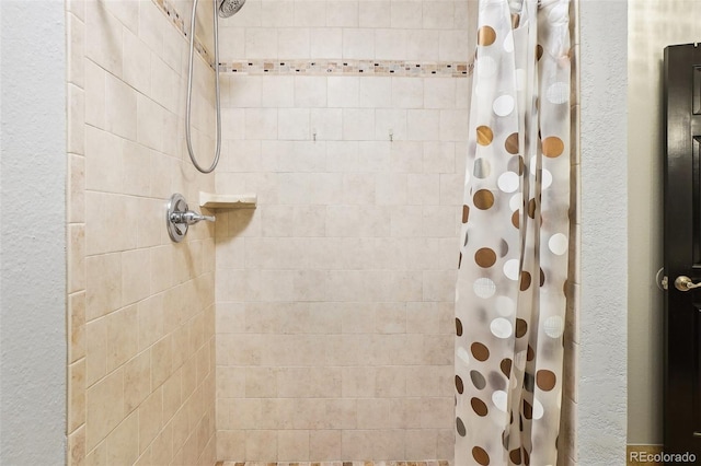 bathroom featuring a textured wall and tiled shower