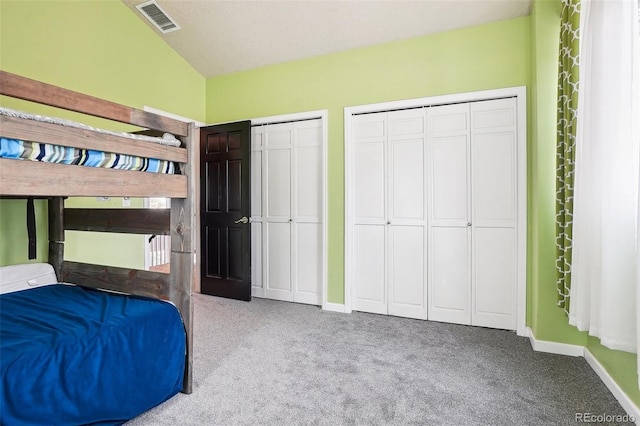 unfurnished bedroom featuring carpet floors, baseboards, two closets, and visible vents