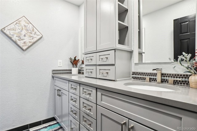 full bathroom featuring a sink, tasteful backsplash, a textured wall, and double vanity