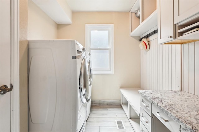 laundry area with separate washer and dryer, cabinet space, visible vents, and light wood-type flooring