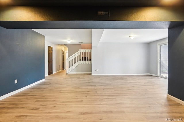 spare room featuring stairway, baseboards, and light wood-type flooring
