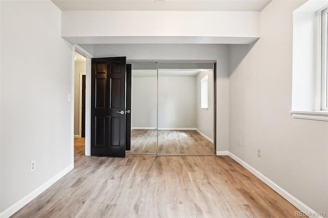 unfurnished bedroom featuring baseboards, a closet, and wood finished floors