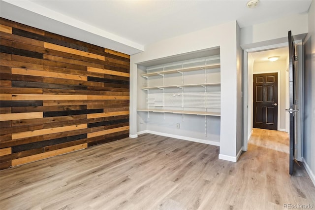 interior space featuring wooden walls, baseboards, and wood finished floors