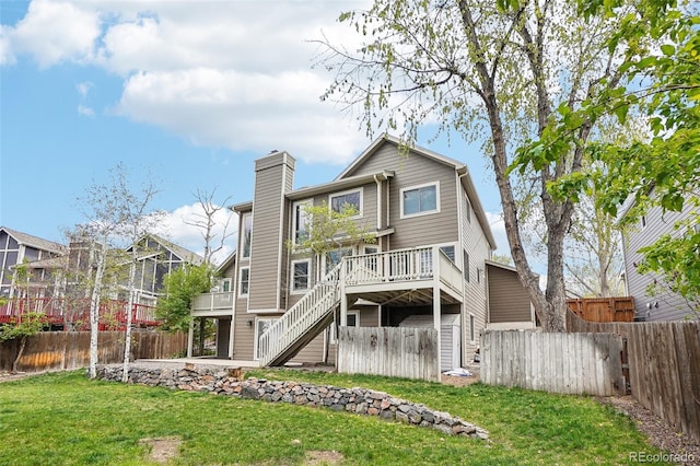 back of property featuring stairway, a deck, fence, and a lawn