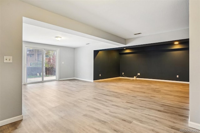 empty room with baseboards, visible vents, and wood finished floors
