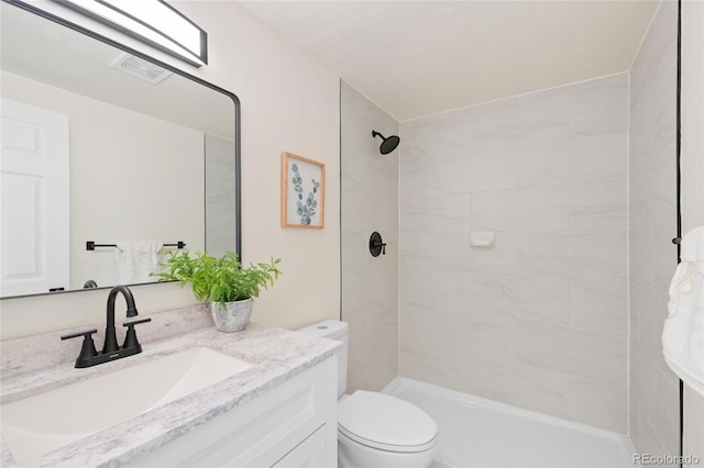 bathroom with vanity, a tile shower, and toilet