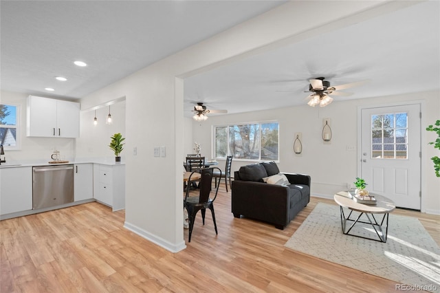 kitchen featuring white cabinetry, dishwasher, a healthy amount of sunlight, and light wood-type flooring