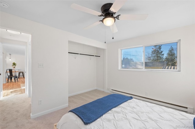 carpeted bedroom with ceiling fan, a baseboard radiator, and a closet