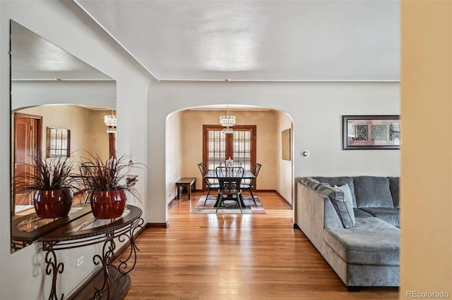 interior space with baseboards, arched walkways, an inviting chandelier, and wood finished floors