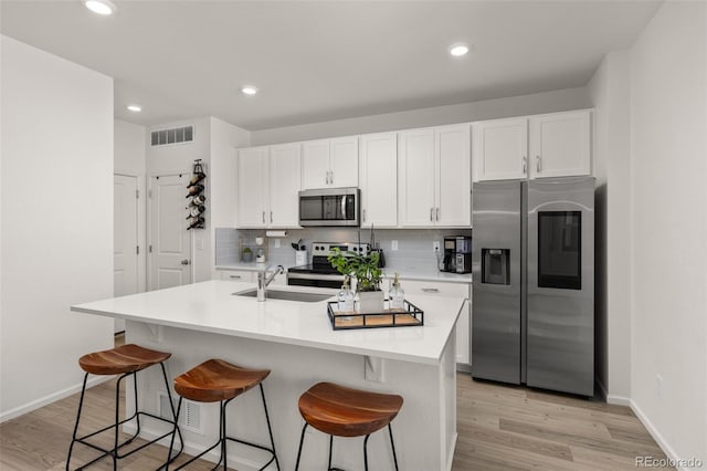 kitchen featuring sink, a center island with sink, white cabinets, and appliances with stainless steel finishes