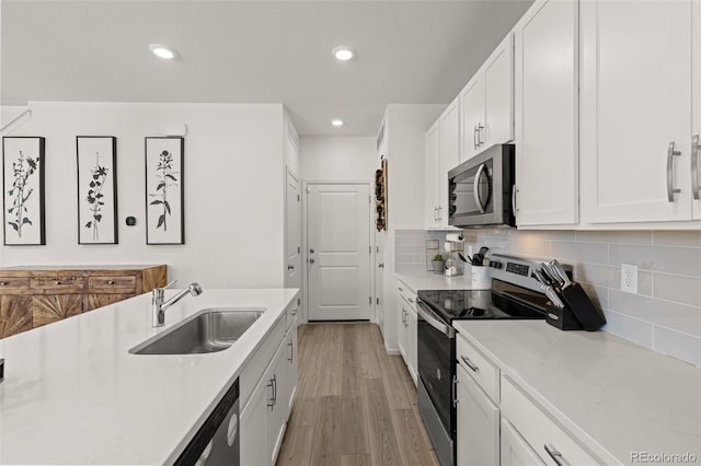 kitchen with tasteful backsplash, stainless steel appliances, sink, and white cabinets