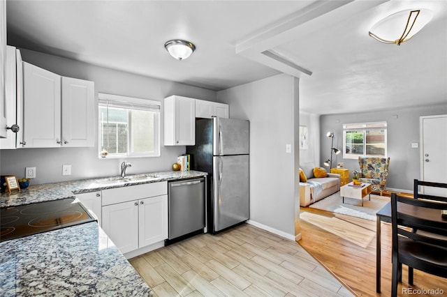 kitchen with light hardwood / wood-style flooring, white cabinets, stainless steel appliances, and light stone counters