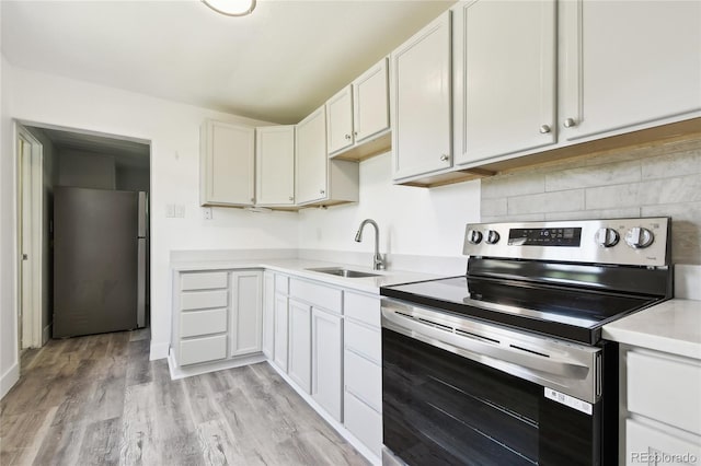 180 S Lamar St, Lakewood, CO 80226 - kitchen featuring appliances with stainless steel finishes, a sink, light countertops, decorative backsplash, and light wood-style flooring