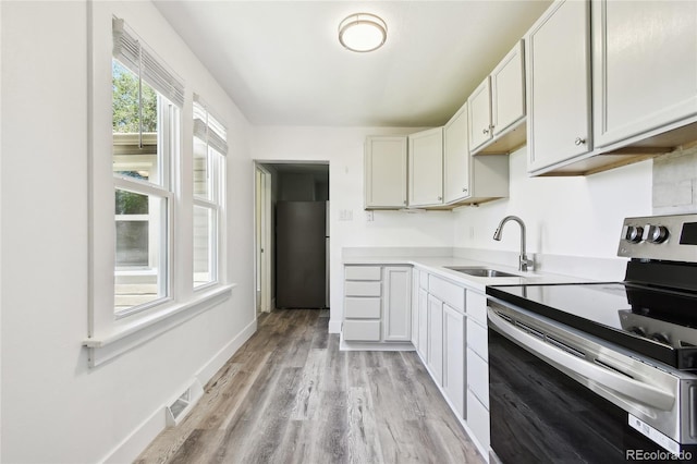180 S Lamar St, Lakewood, CO 80226 - kitchen with stainless steel appliances, a sink, light wood-type flooring, light countertops, and white cabinetry