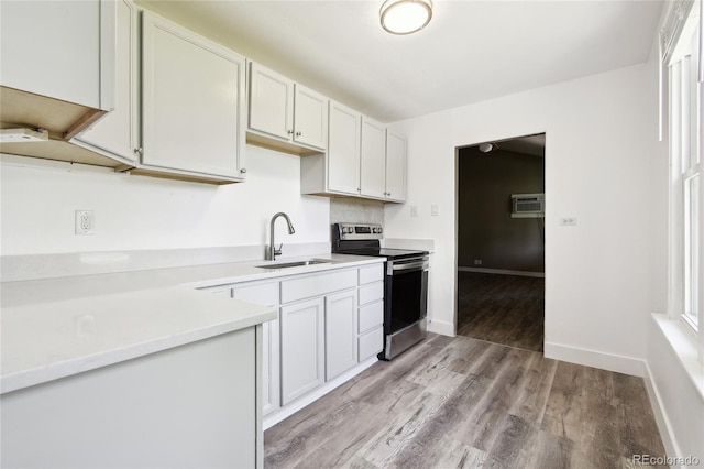 180 S Lamar St, Lakewood, CO 80226 - kitchen featuring stainless steel range with electric cooktop, a sink, light wood-type flooring, light countertops, and a wall mounted air conditioner