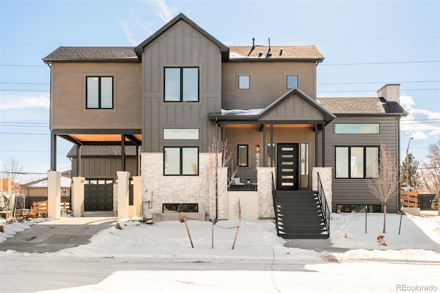 view of front of house with an attached garage, a shingled roof, a porch, and board and batten siding