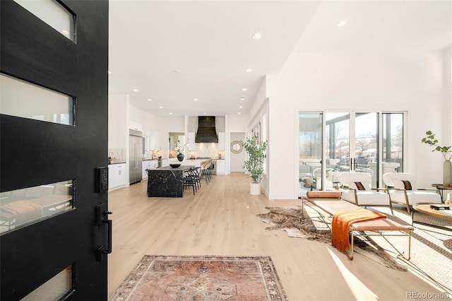 living area with a towering ceiling, light wood-style flooring, and recessed lighting