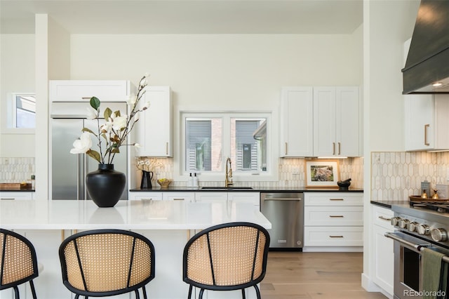 8230 W Tennessee Ct, Lakewood, CO 80226 - kitchen with stainless steel appliances, extractor fan, a sink, a kitchen breakfast bar, and white cabinetry