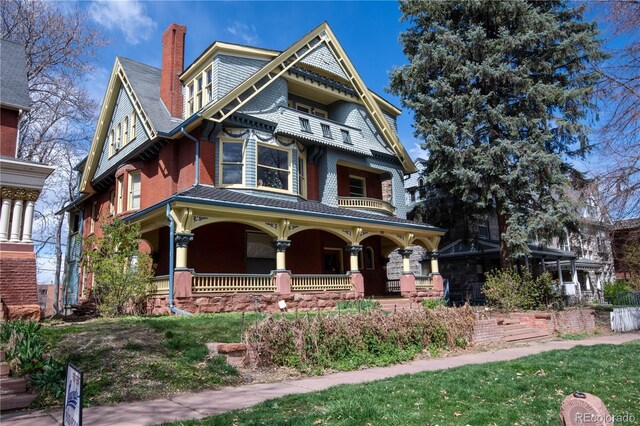 victorian home with a balcony, a porch, and a chimney