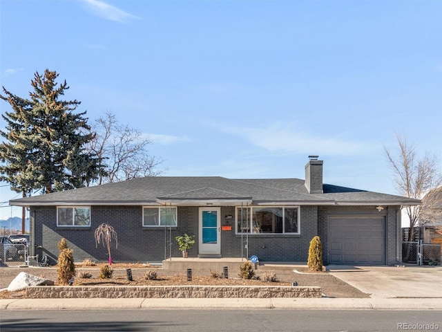 ranch-style home featuring concrete driveway, brick siding, a chimney, and an attached garage