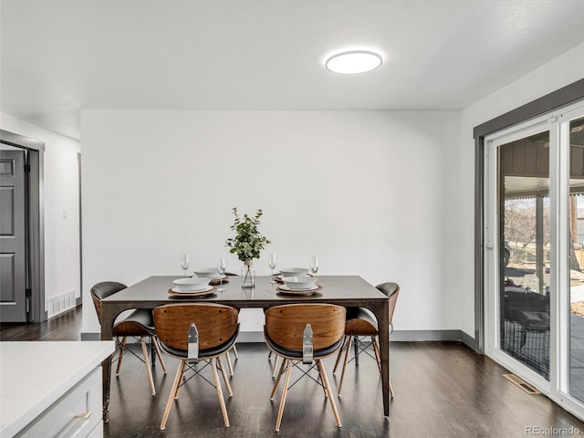 dining space with dark wood-style flooring, visible vents, and baseboards