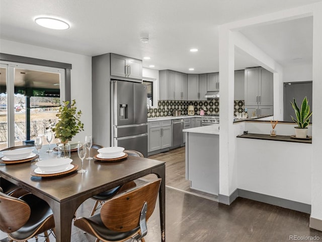 kitchen featuring dark wood-style floors, tasteful backsplash, stainless steel appliances, and gray cabinetry