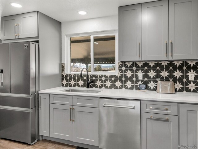 kitchen with stainless steel appliances, a sink, and gray cabinetry