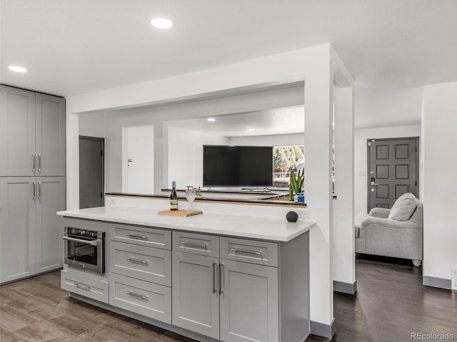 kitchen featuring oven, recessed lighting, dark wood-type flooring, and gray cabinetry