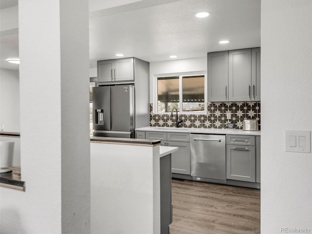 kitchen featuring stainless steel appliances, wood finished floors, gray cabinets, and a sink