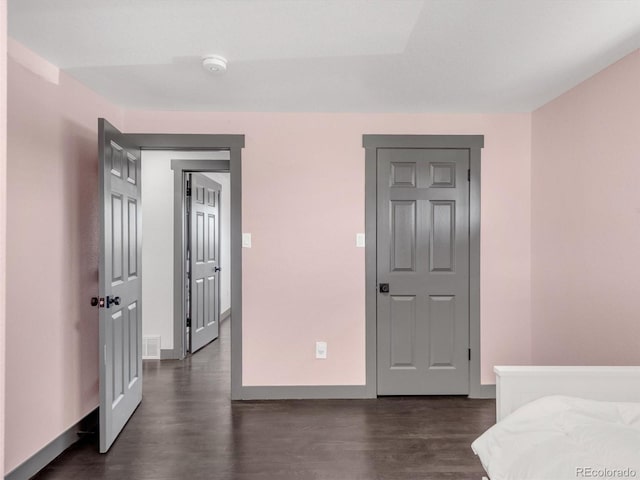 bedroom with dark wood-style floors, visible vents, and baseboards