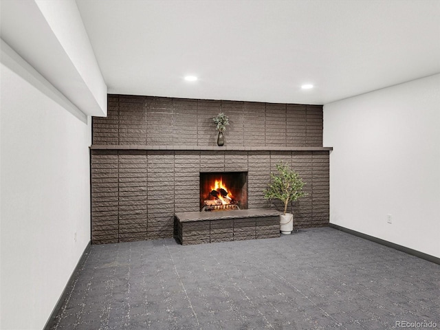 unfurnished living room featuring a brick fireplace, baseboards, and recessed lighting