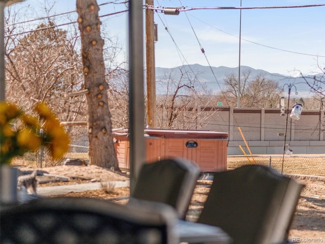 view of yard with fence, a mountain view, and a hot tub