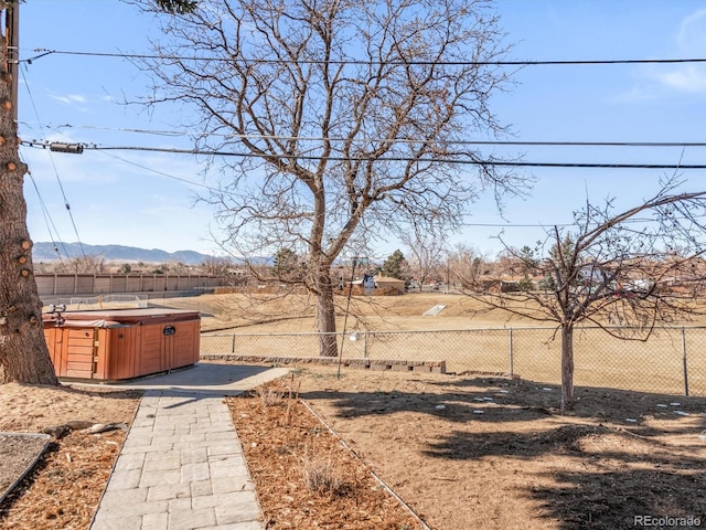 view of yard with a hot tub, a mountain view, and a fenced backyard