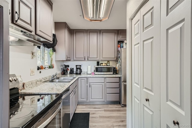 kitchen featuring gray cabinetry, sink, stainless steel appliances, light hardwood / wood-style flooring, and exhaust hood